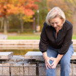 injured adult woman clutching knee